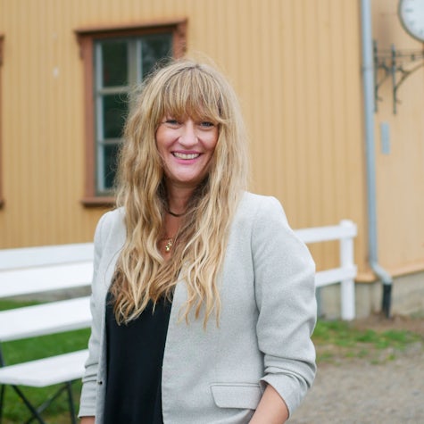 Psykologspesialist Ann-Elizabeth Wiig står smilende foran et bygg med Sørumsand skrevet på veggen.